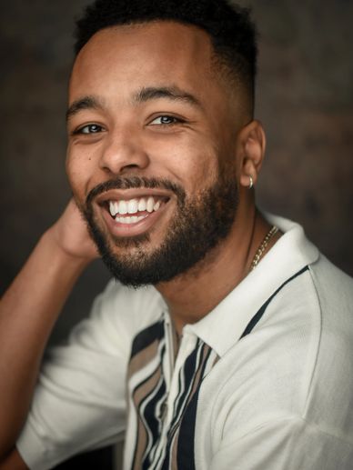 Smiling man with beard and earring in a casual striped shirt.