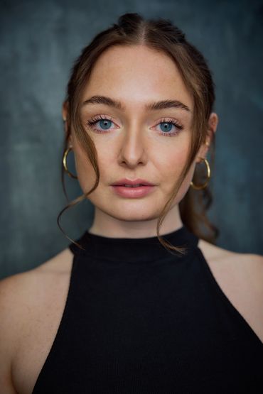 Portrait of a woman with blue eyes and gold hoop earrings.