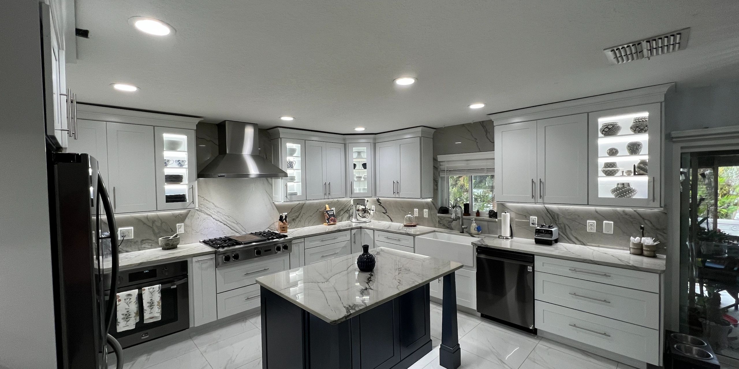 Modern kitchen with white cabinets, marble countertops, and a center island.