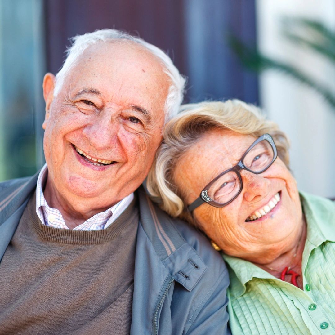 Happy elders, leaning on each other.