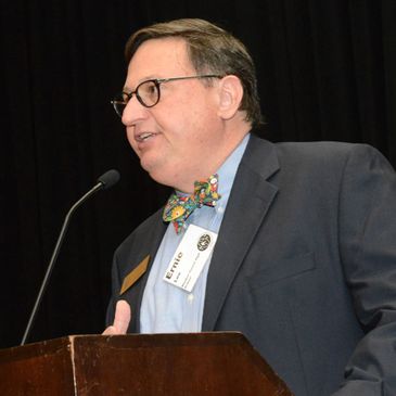 Man in suit speaking at podium with microphone.