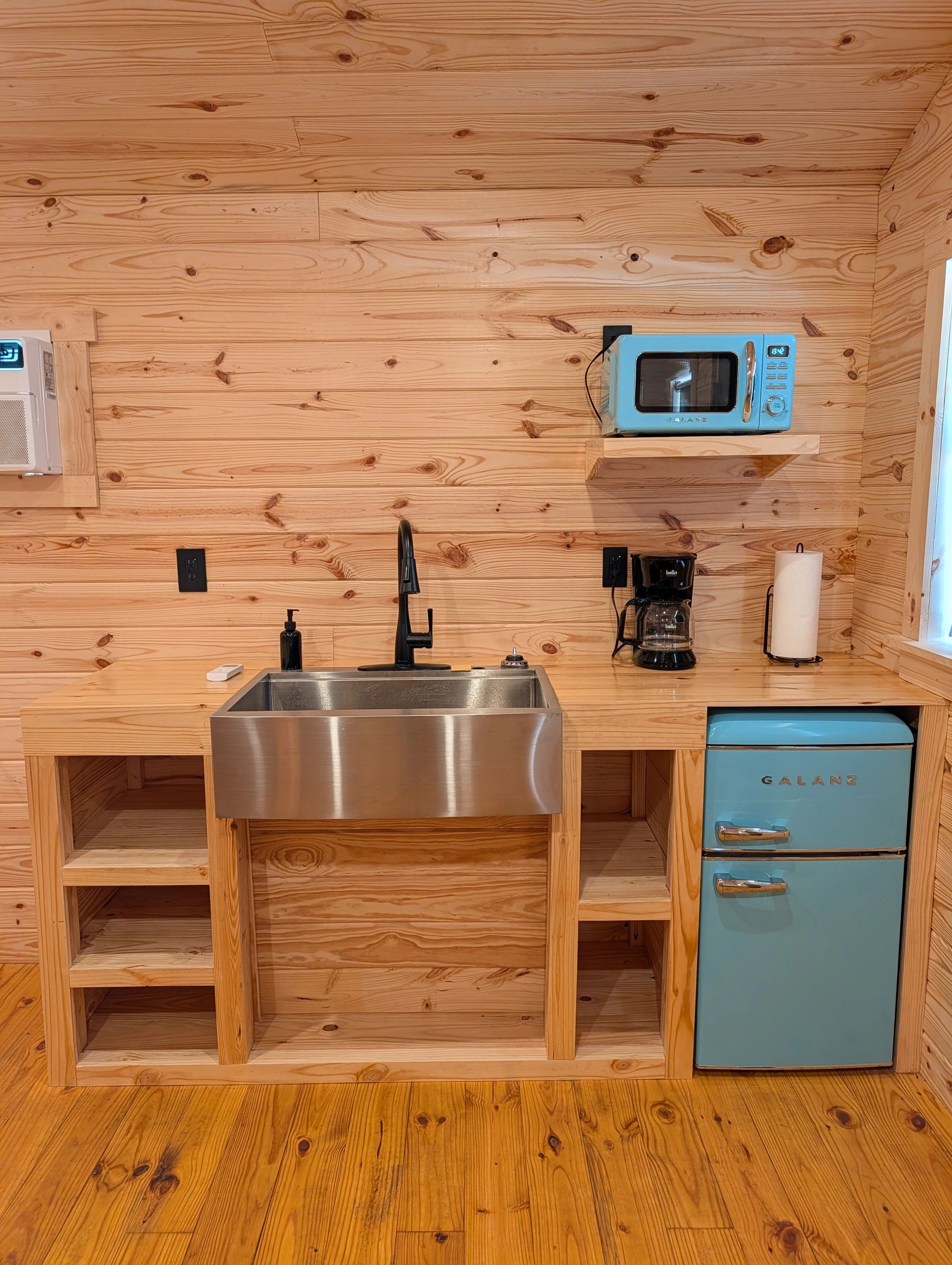 Rustic wooden kitchen with blue retro microwave and fridge.