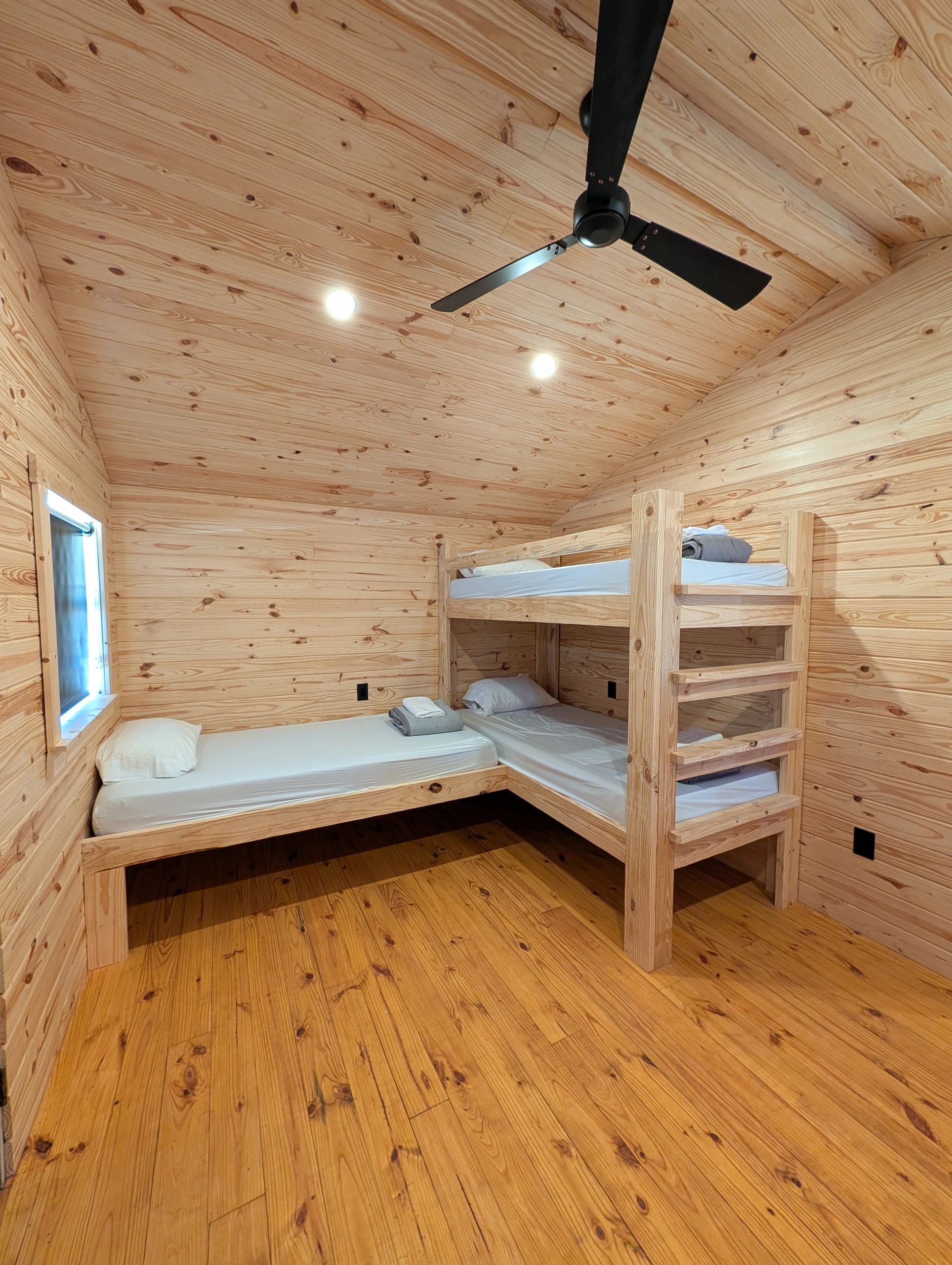 Cozy wooden room with bunk beds and a ceiling fan.