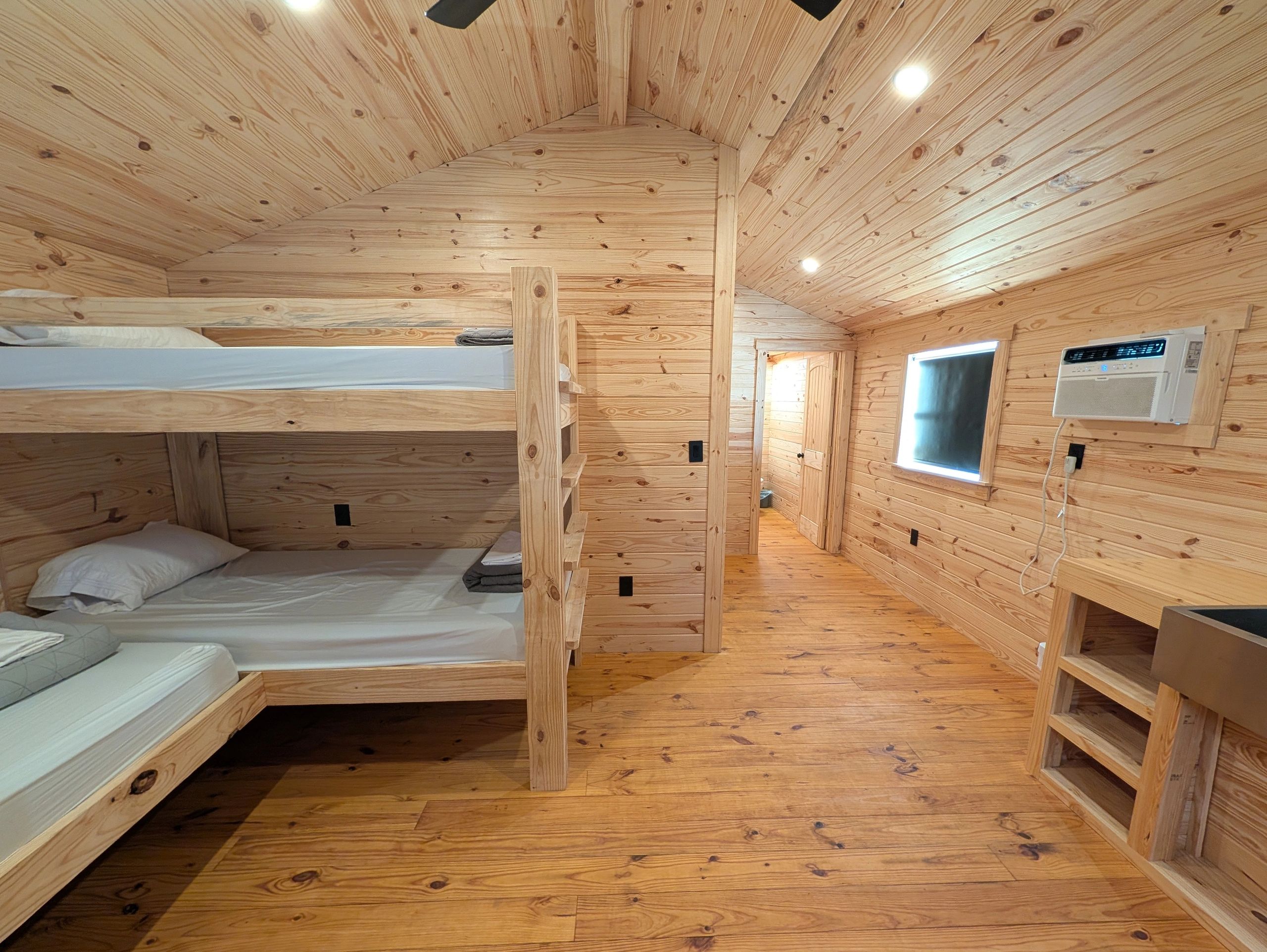 Cozy wooden bunk bed room with natural pine paneling and air conditioning.