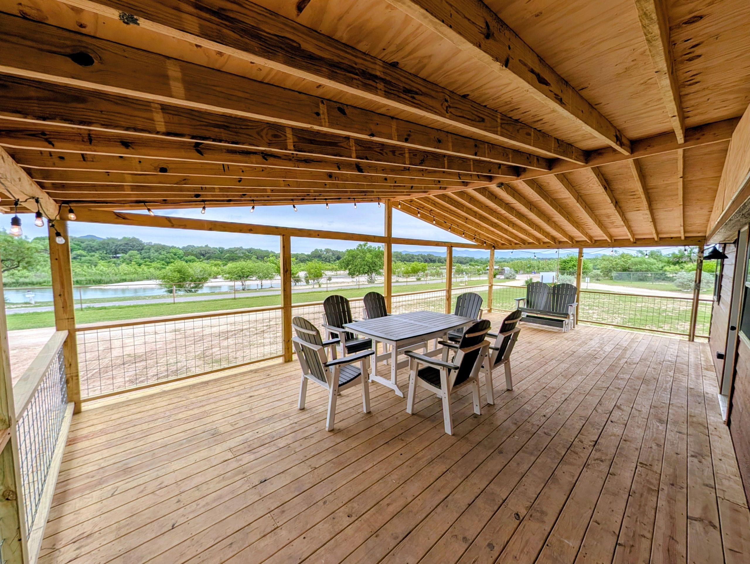 Spacious wooden porch with outdoor dining set and scenic view.
