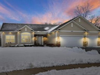 A modern house with snow-covered lawn at sunset.