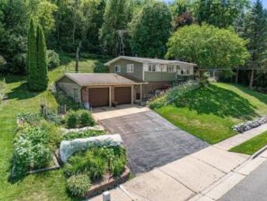 Suburban house with double garage and lush greenery.