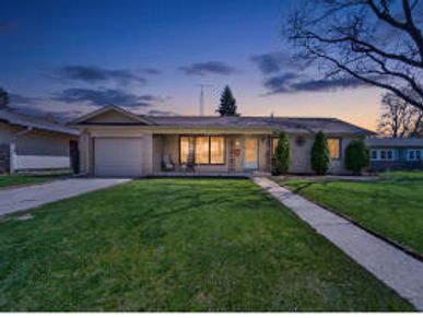 A cozy single-story house at dusk with a well-kept lawn.