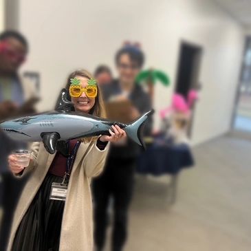 A woman holding a plastic shark. 