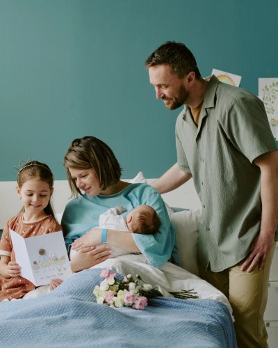 Family celebrating the arrival of a newborn in a hospital room.