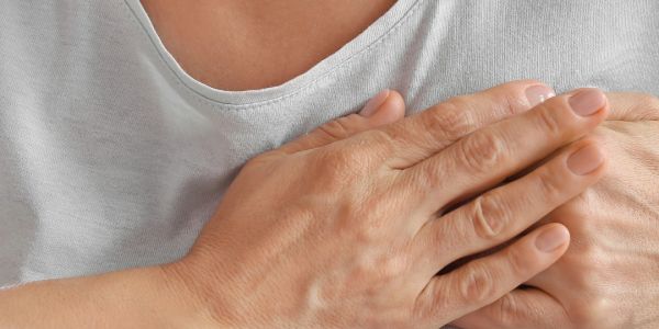 Person clutching chest, possibly indicating chest pain or discomfort.