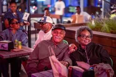 Smiling elderly couple enjoying a night out at a lively outdoor venue.