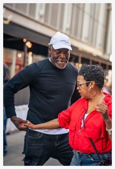 A couple enjoys dancing together on a city street.