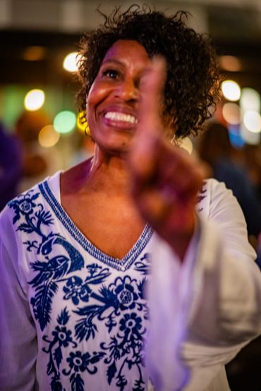 Smiling woman pointing with a blurred background of lights.