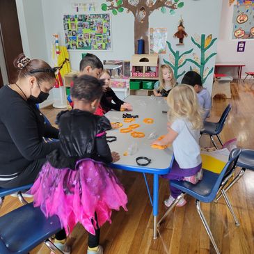 Children and a teacher engaging in a classroom activity with playdough and cookie cutters.