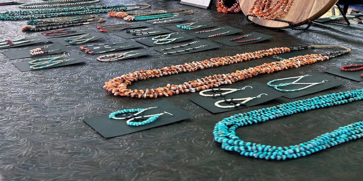 Handcrafted necklaces and earrings displayed on a textured black surface.
