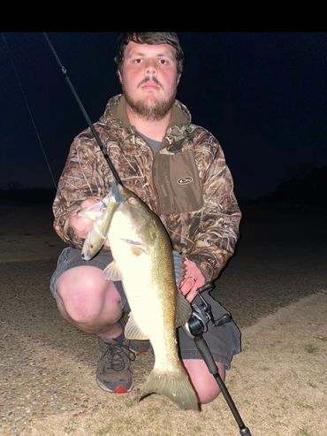 Young man holding a large fish at night.
