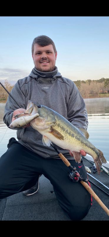 Man holding a large fish by the lake.