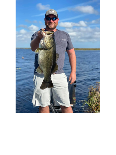 Man holding a large fish by the water.