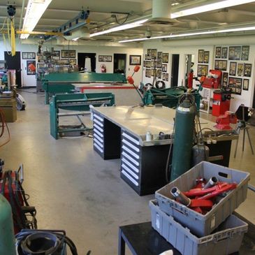 A spacious, well-lit workshop filled with tools, machines, and workbenches.