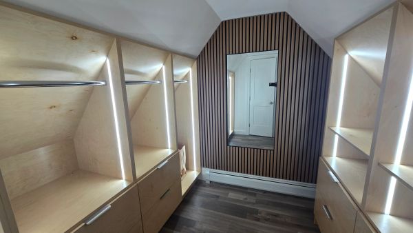 Modern walk-in closet with wooden shelves, LED lighting, and a full-length mirror.