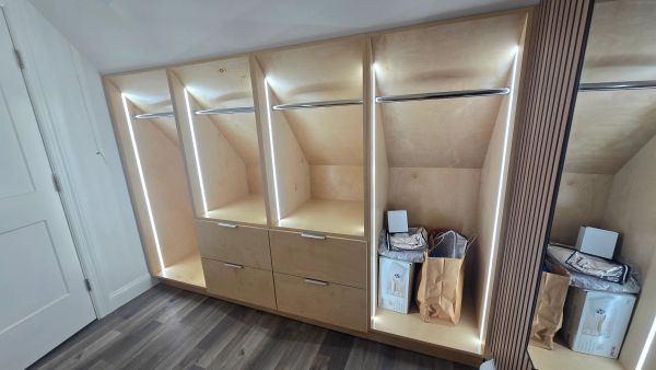 Modern wooden wardrobe with LED lighting and storage compartments.
