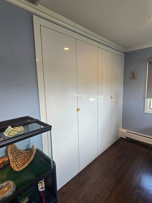 White closet doors with yellow tape handles in a blue room with wooden floor.