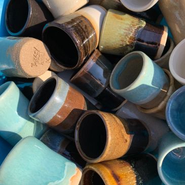 A collection of colorful ceramic mugs piled together.