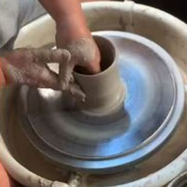Hands shaping clay on a spinning pottery wheel.