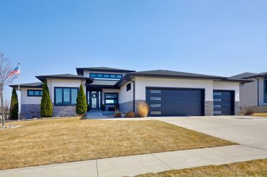 Modern single-story house with a three-car garage and manicured lawn.