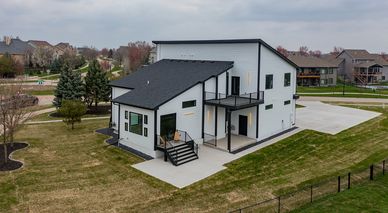 Modern two-story house with black and white exterior and spacious yard.