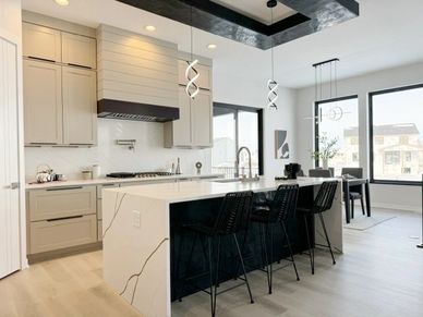 Modern kitchen with a sleek island and black bar stools.