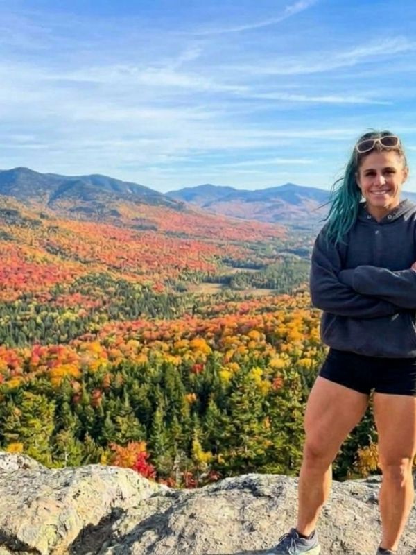 Woman standing on a cliff overlooking colorful autumn forest.