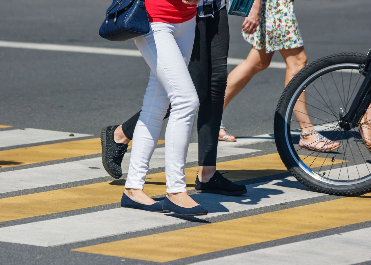 Pedestrians and bicycle crossing intersection at crosswalk. 