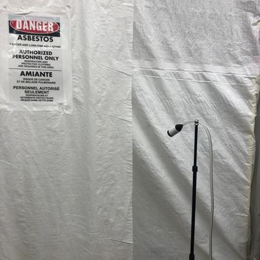 Warning sign on asbestos containment with mic stand.