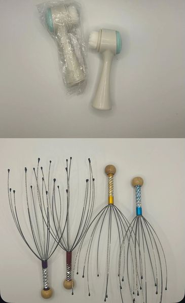 Two facial cleansing brushes and four metal head massagers on a white surface.