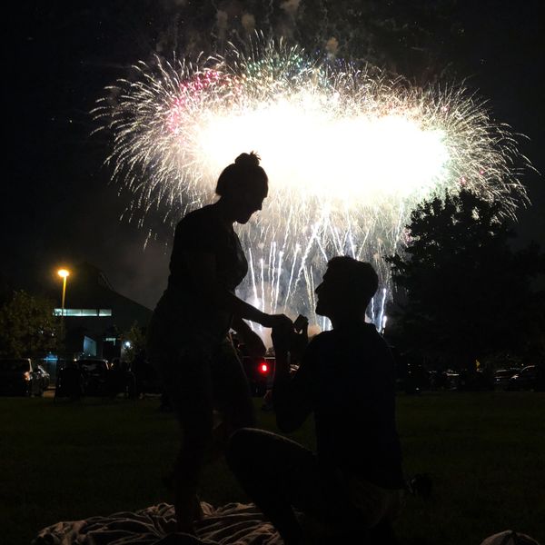 Silhouetted couple with fireworks lighting up the night sky.