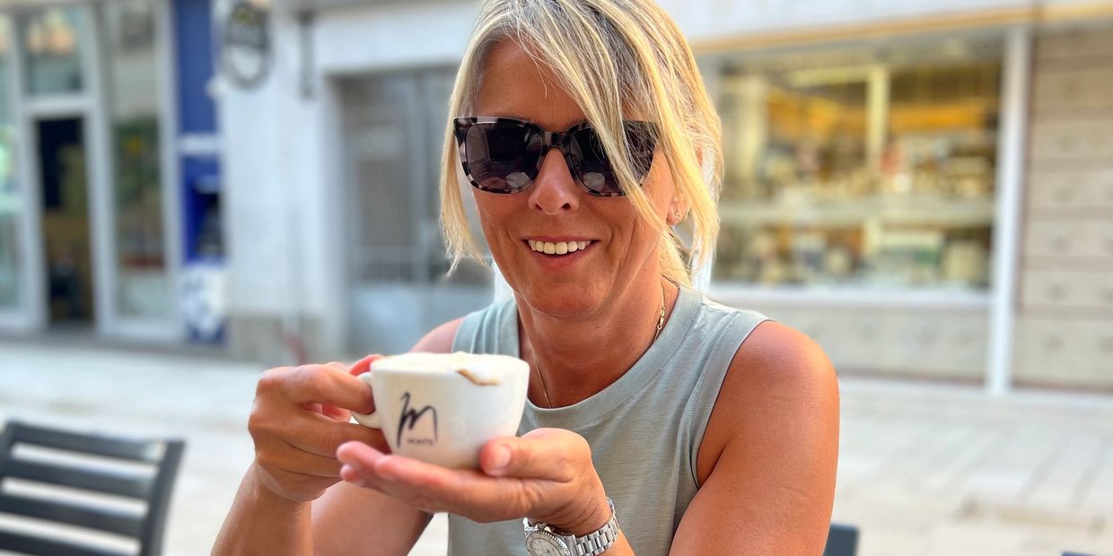 Woman with sunglasses enjoying a cup of coffee outdoors.