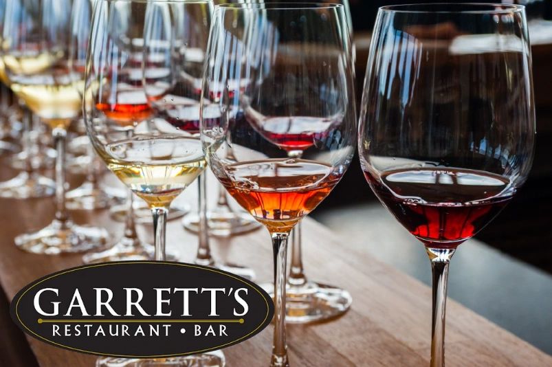 Wine glasses lined up on a wooden table at Garrett's Restaurant Bar.