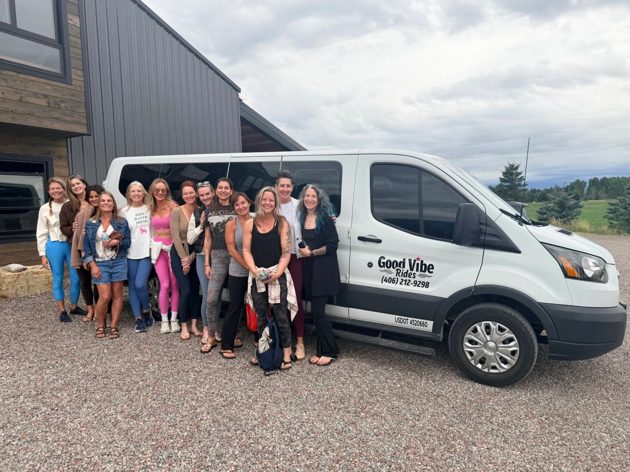 Group of women posing by a white shuttle van.
