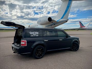Black van parked near a private jet on runway.