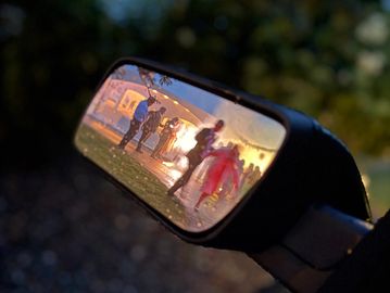 People seen in a rearview mirror at sunset.