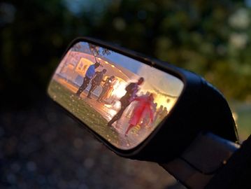 People seen in a rearview mirror at sunset.