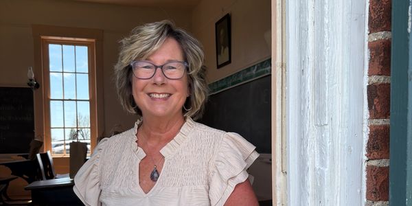 Smiling woman standing in a doorway with glasses.