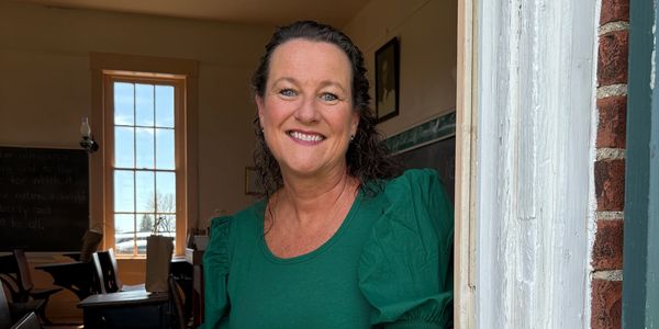 Smiling woman in green top by a door.