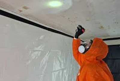 Person in hazmat suit inspecting ceiling.