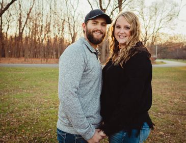 A couple holding hands and smiling outdoors in fall.