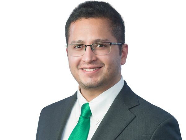 Professional man wearing glasses, suit, and green tie.