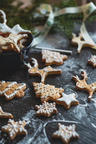 Holiday-themed gingerbread cookies with icing on a dark surface.