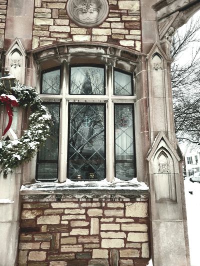 Snow-covered wreath and Gothic-style window on a brick building.
